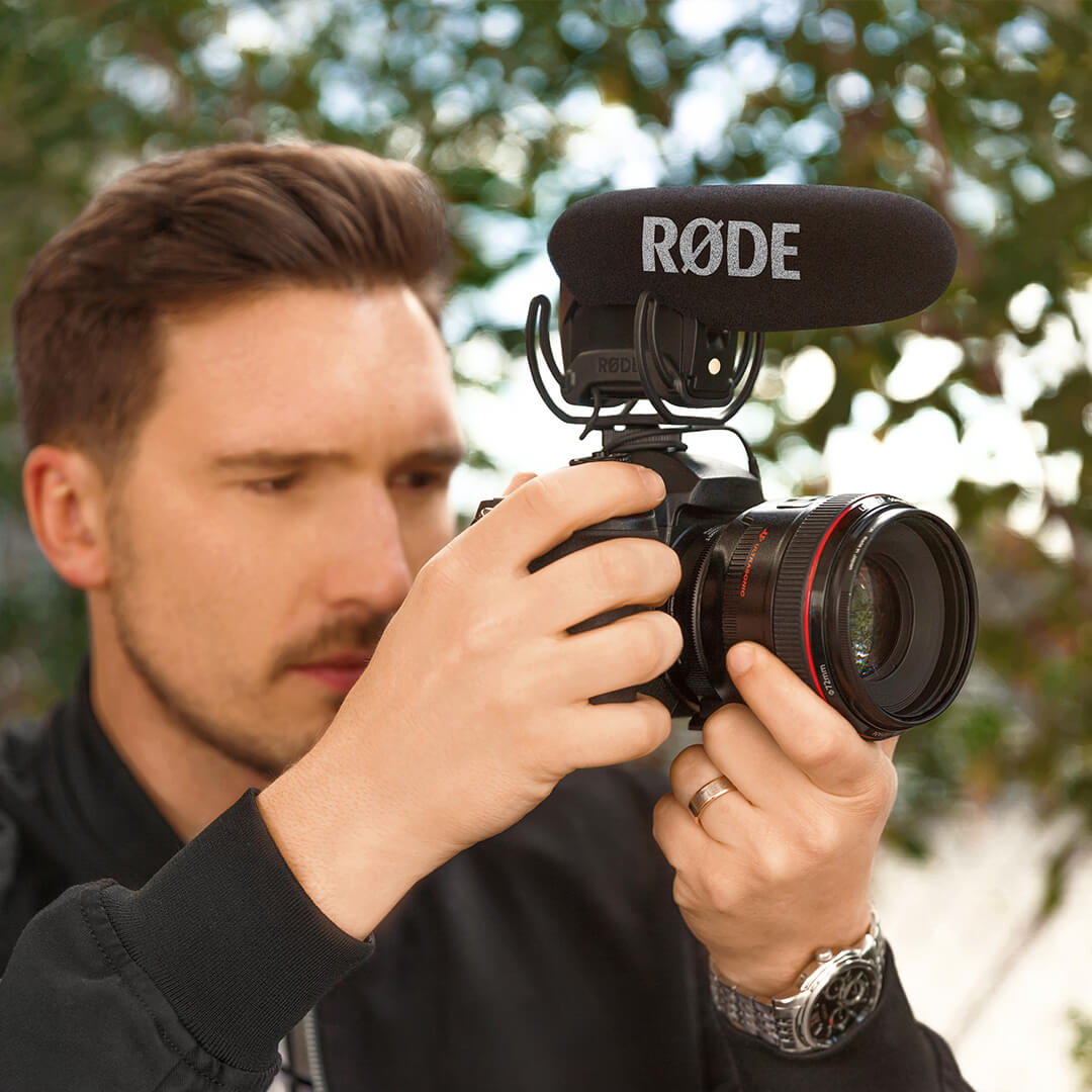man holding camera with video mic pro microphone on mount.