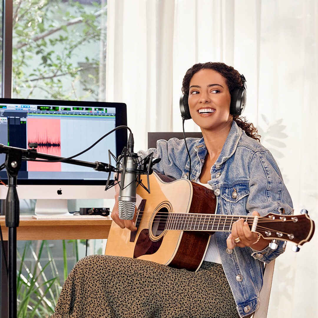 Girl wearing NTH-100 recording acoustic guitar with NT1-A