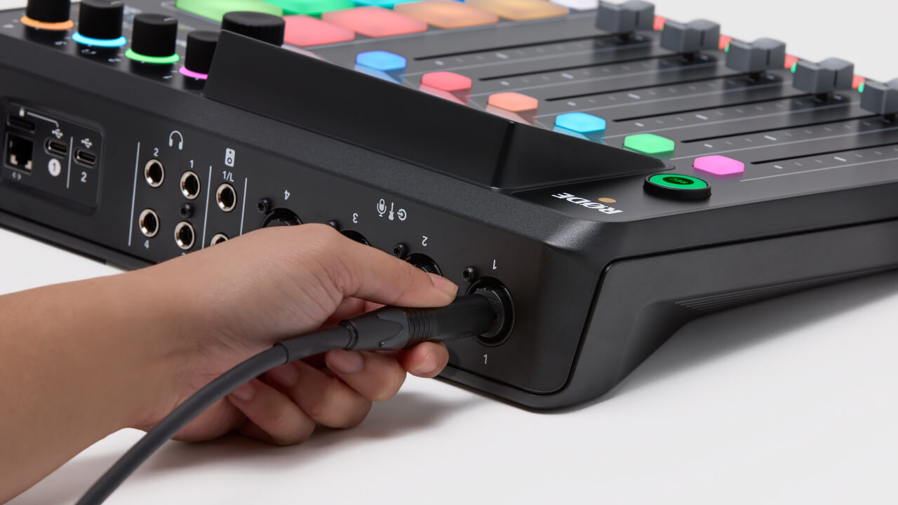 Hand connecting TRS cable to back of RØDECaster Pro II