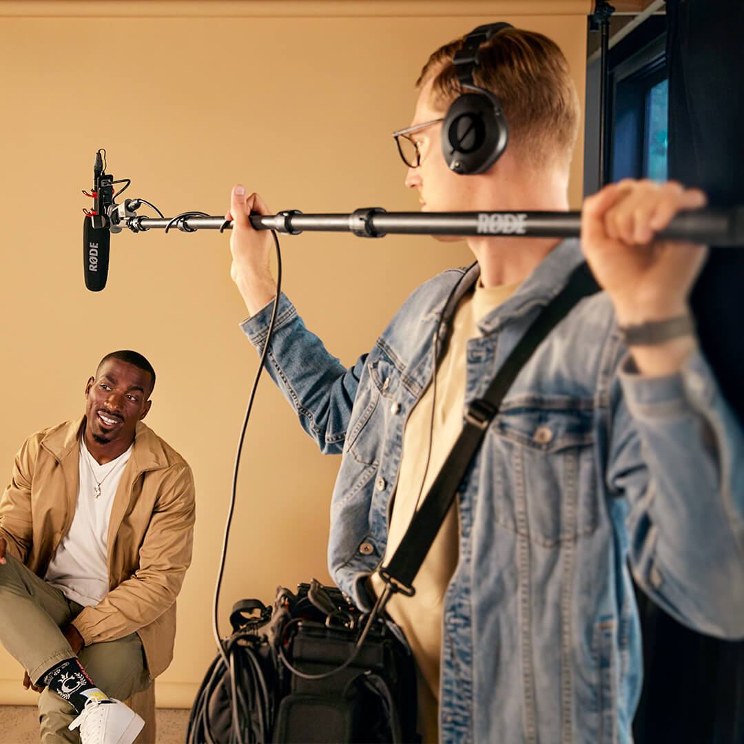 Boom operator with shotgun microphone above man