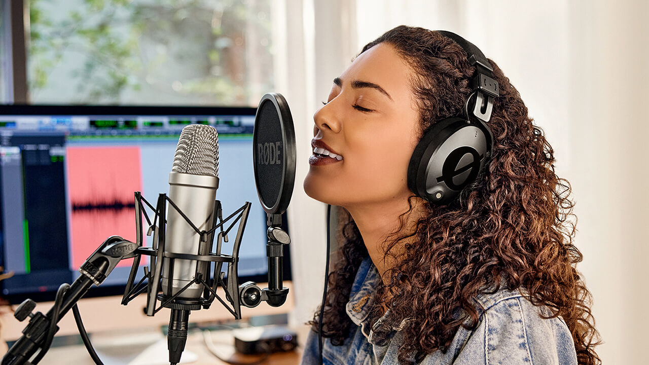 Girl wearing NTH-100 singing into NT1-A with Pro Tools on computer screen in the background